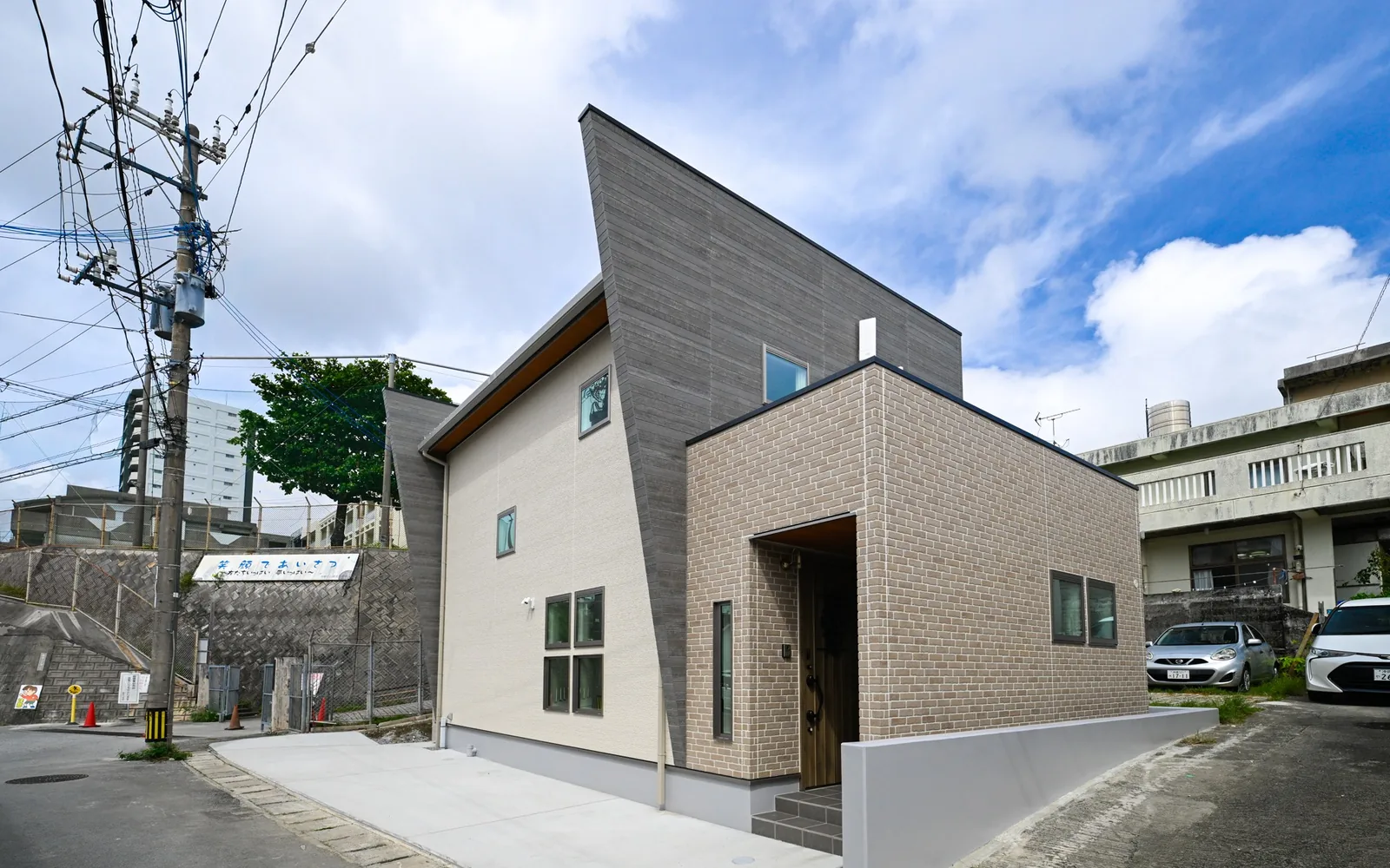 那覇市識名の阿波根邸の昼の外観。グレーとレンガ調の外壁を組み合わせた木造2階建て住宅